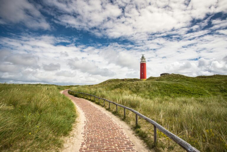 wandelingen in Nederland en België. Wandeling op Texel in Nederland, rode vuurtoren, stenen pad door duinen
